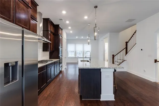 a kitchen with stainless steel appliances granite countertop a refrigerator a sink and a stove