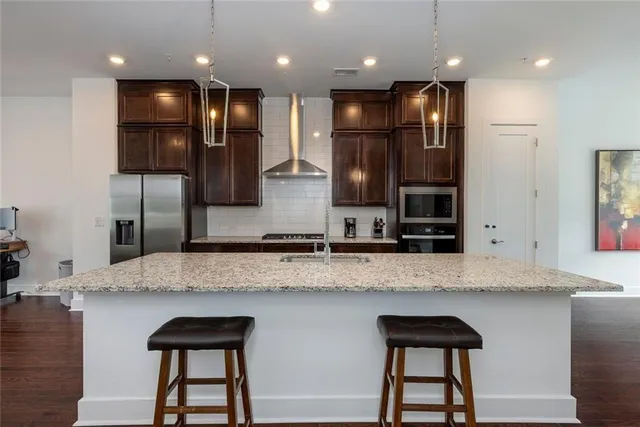 a kitchen with stainless steel appliances granite countertop a refrigerator a sink and a stove