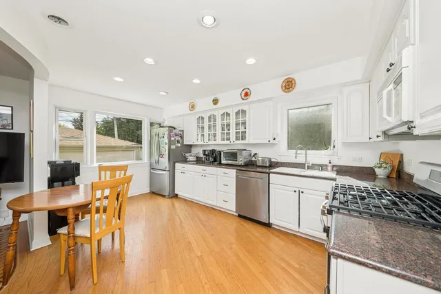 a kitchen with stainless steel appliances granite countertop a stove top oven a sink a dining table and chairs