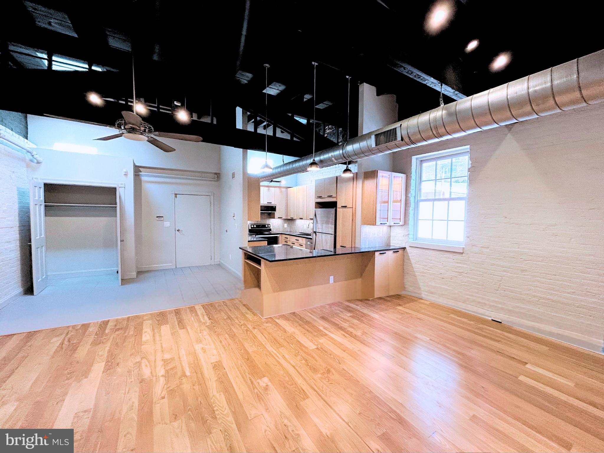 28 East Patrick Street, Unit 2 Frederick, MD 21701 - Photo 9 of 13 a kitchen with stainless steel appliances kitchen island granite countertop a sink cabinets and wooden floor