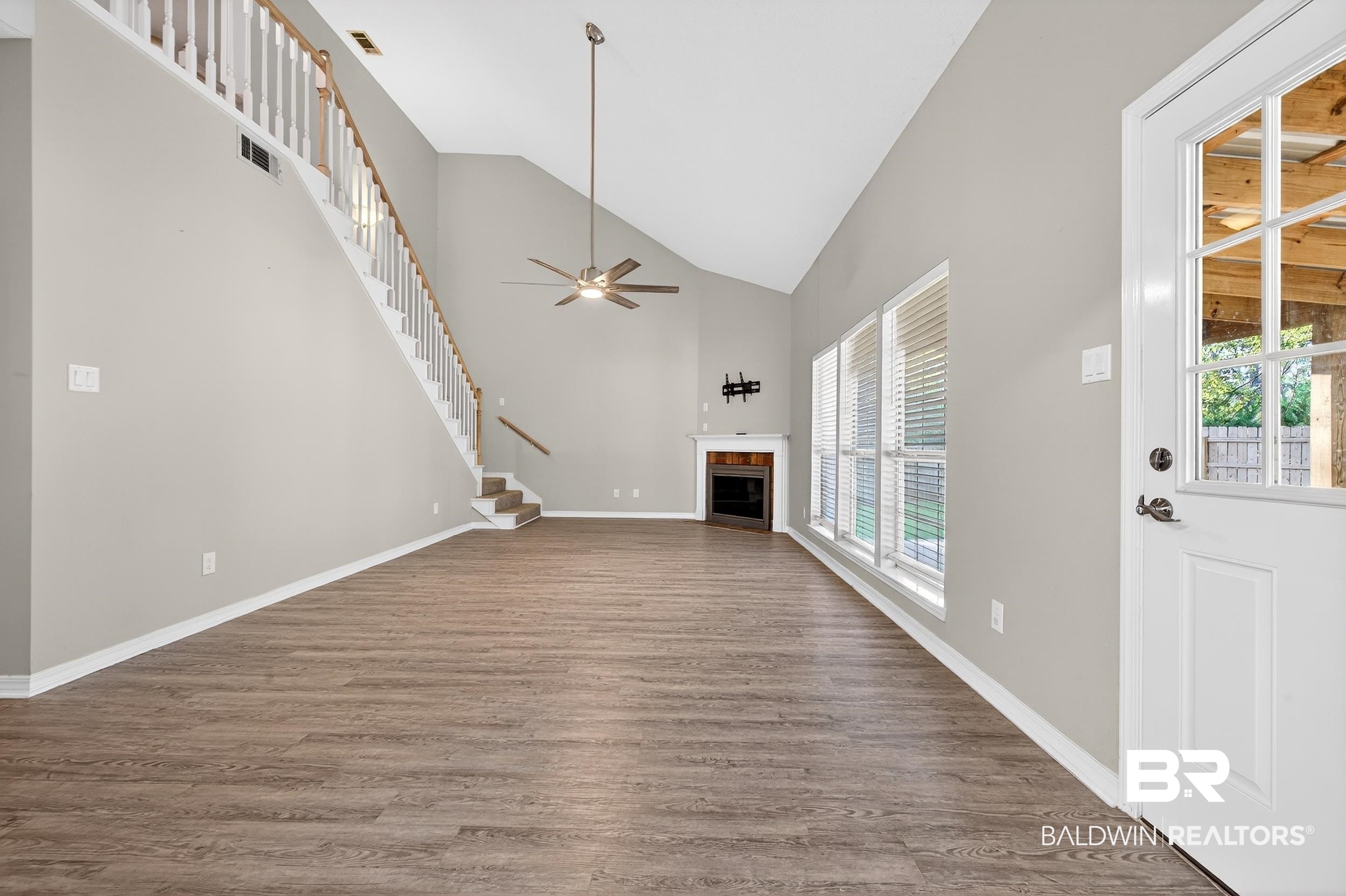 7050 Highpointe Place West Daphne, AL 36527 - Photo 25 of 66 Unfurnished living room with lofted ceiling, a fireplace with flush hearth, dark wood-style floors, and ceiling fan