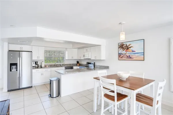 a kitchen with stainless steel appliances granite countertop a stove a refrigerator a dining table and chairs