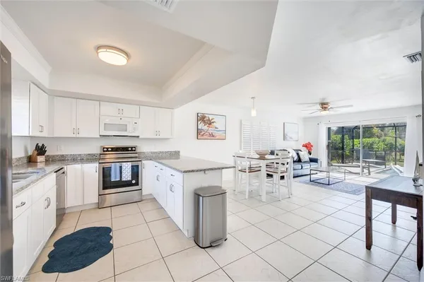 a large kitchen with white cabinets a stove a dining table and chairs