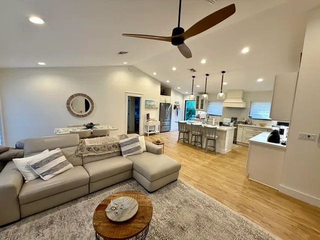 a living room with furniture kitchen view and a wooden floor
