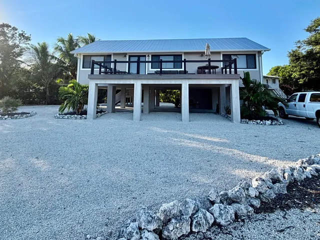 a view of house with a yard and a car park in front of it