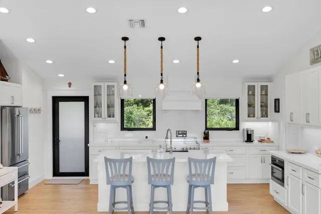 a kitchen with stainless steel appliances kitchen island granite countertop a sink and a refrigerator