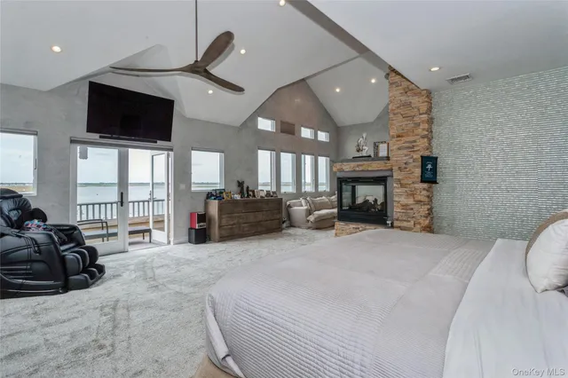 a large bedroom with furniture a flat screen tv and a fireplace