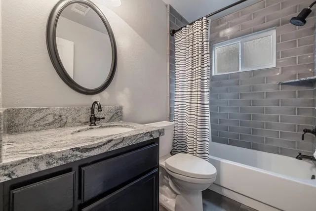 a bathroom with a granite countertop toilet a sink and a bathtub