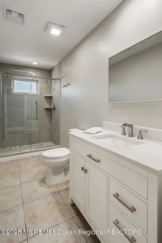 a bathroom with a granite countertop sink a toilet a mirror and shower