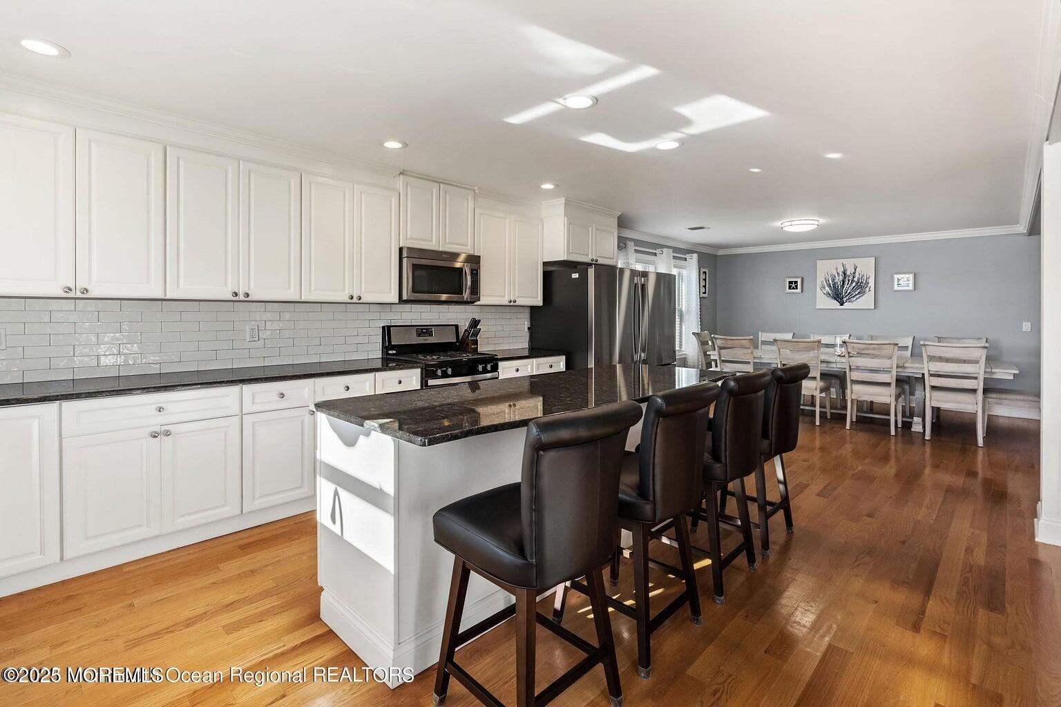 32 Niblick Street Point Pleasant Beach, NJ 08742 - Photo 6 of 31 a kitchen with stainless steel appliances granite countertop a stove a refrigerator a sink a dining table and chairs with wooden floor