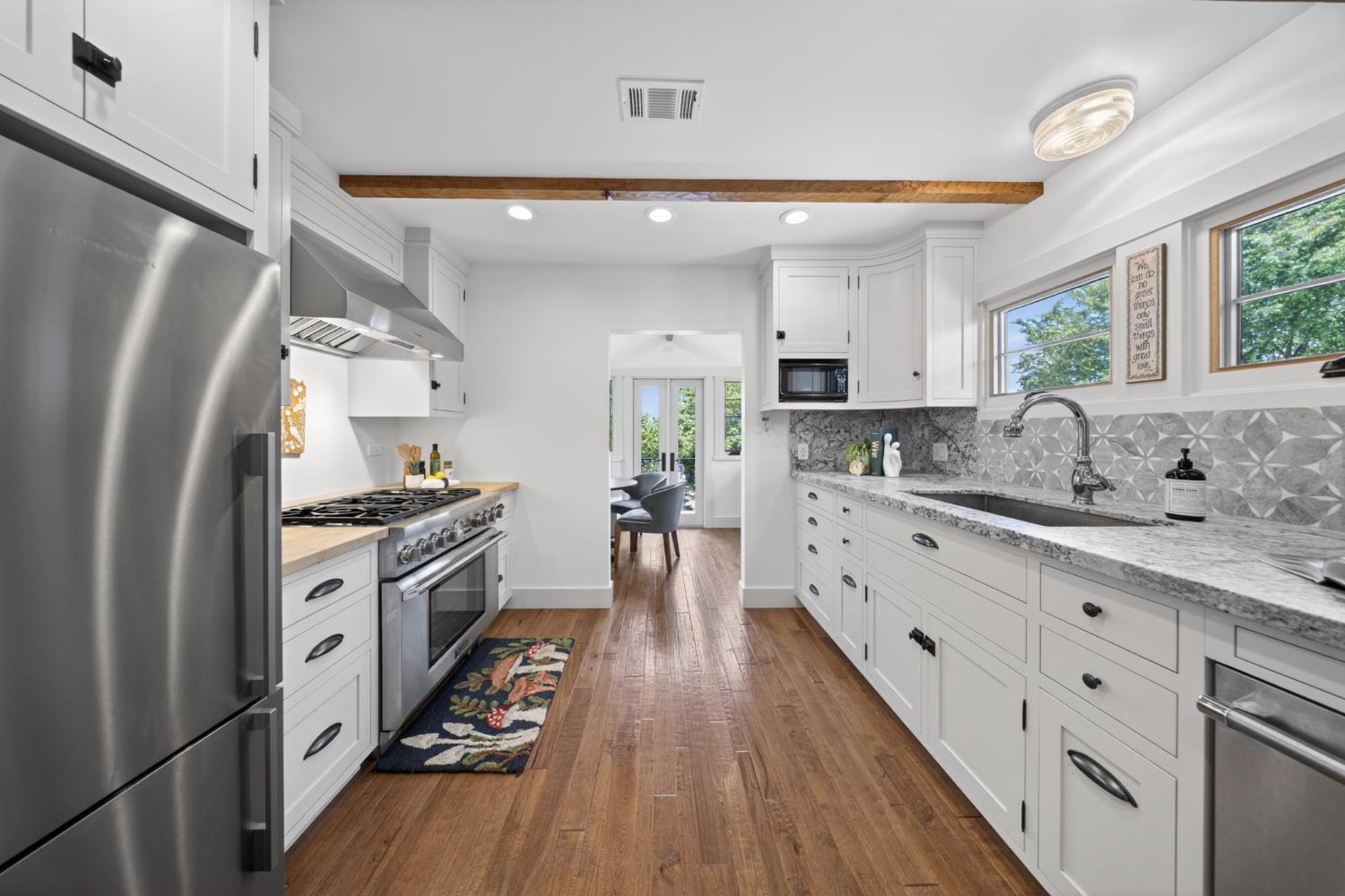 14621 East 8 Mile Road Linden, CA 95236 - Photo 27 of 38 a kitchen with granite countertop a refrigerator a sink dishwasher a stove and white cabinets with wooden floor