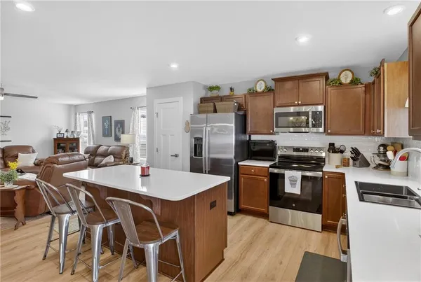 a kitchen with stainless steel appliances kitchen island granite countertop a sink dishwasher a stove a refrigerator with island and chairs