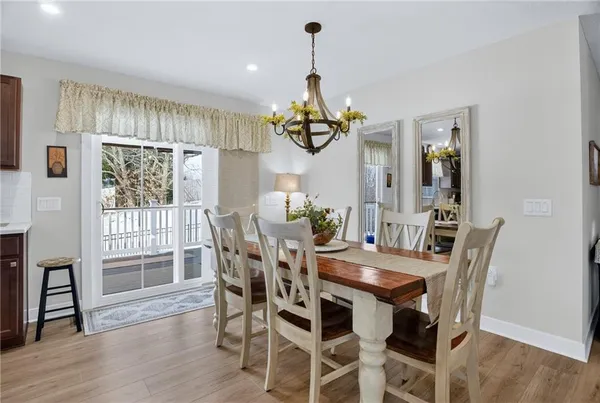a dining room with wooden floor a chandelier a wooden table and chairs