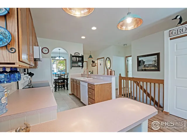a living room with stainless steel appliances kitchen island a table chairs in it and wooden floor