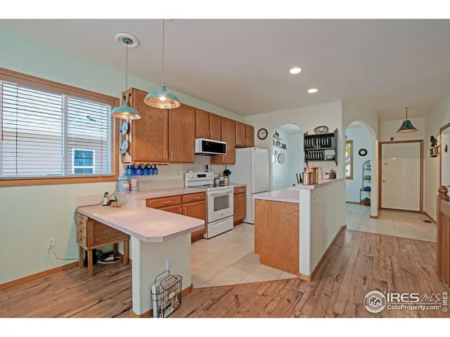 a kitchen with a refrigerator a stove top oven a sink dishwasher and wooden cabinets with wooden floor