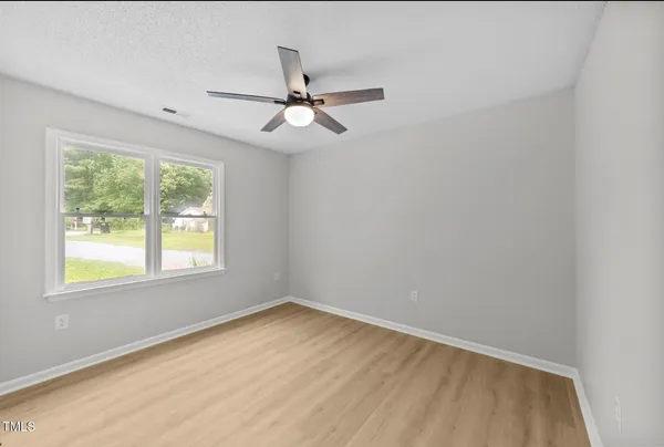an empty room with a window and ceiling fan
