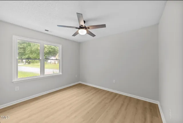 an empty room with a window and ceiling fan