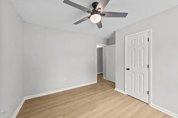 an empty room with wooden floor fan and windows