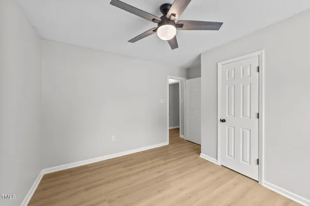 an empty room with wooden floor fan and windows