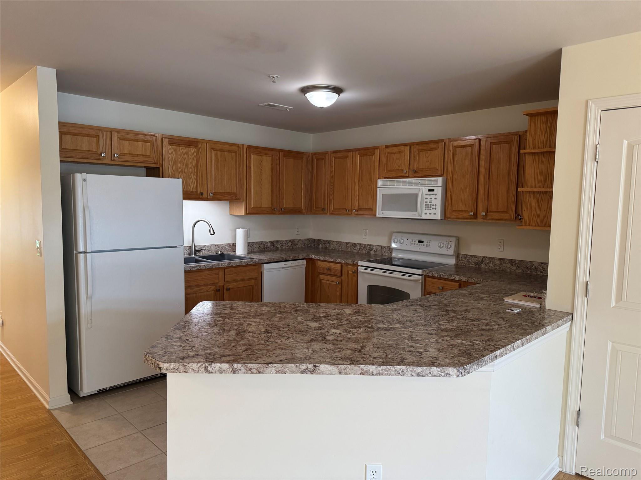 34086 Utica Road Fraser, MI 48026 - Photo 4 of 12 Kitchen with white appliances, a peninsula, wood finish cabinetry, open shelves, and light tile patterned floors