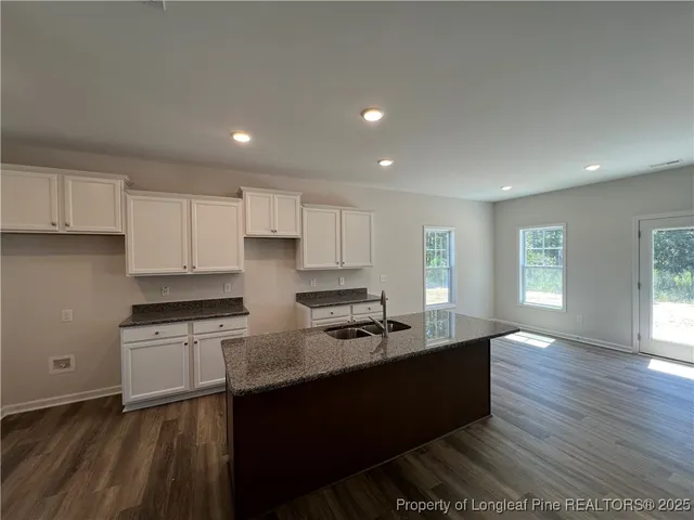 a kitchen with granite countertop a sink cabinets and wooden floor