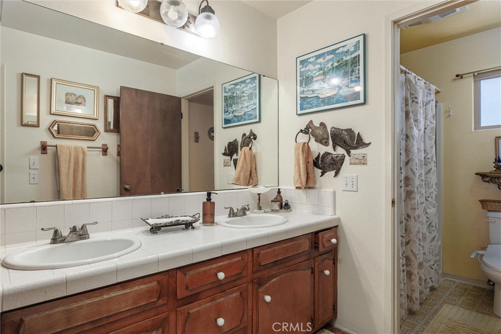 2023 Circle Cayucos, CA 93430 - Photo 13 of 44 a bathroom with double vanity sinks a toilet a mirror and shower