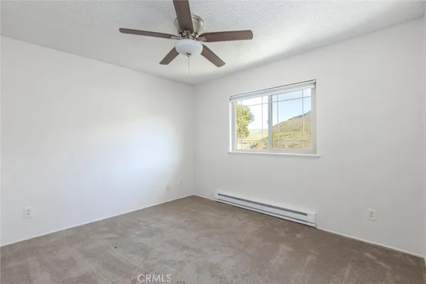 an empty room with a window and ceiling fan