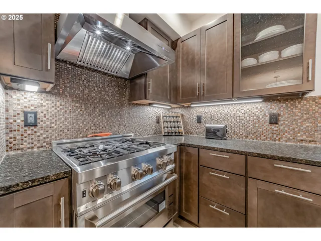 a kitchen with granite countertop a stove a sink dishwasher and cabinets