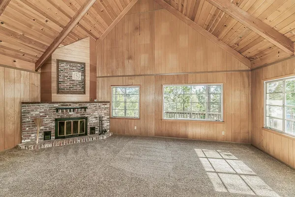 an empty room with windows fireplace and ceiling fan