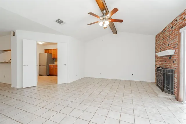 an empty room with chandelier fan and windows