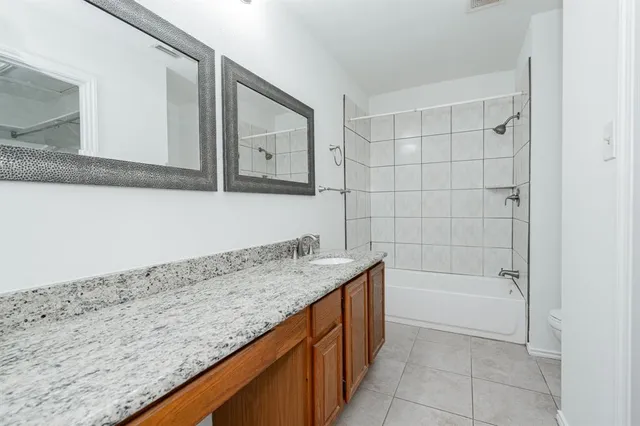 a bathroom with a granite countertop sink a mirror and a bathtub