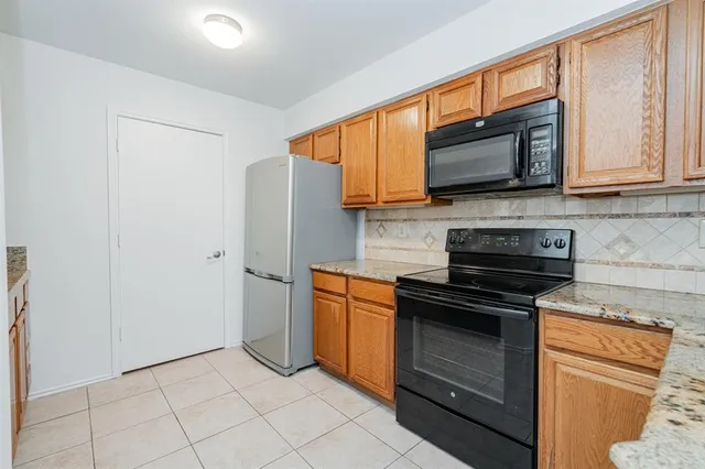 a kitchen with stainless steel appliances granite countertop a stove top oven a sink and a refrigerator