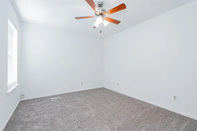an empty room with a window and a ceiling fan