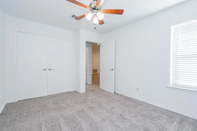 an empty room with closet and a chandelier fan