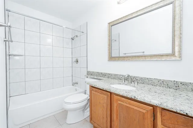 a bathroom with a granite countertop sink a toilet and bathtub