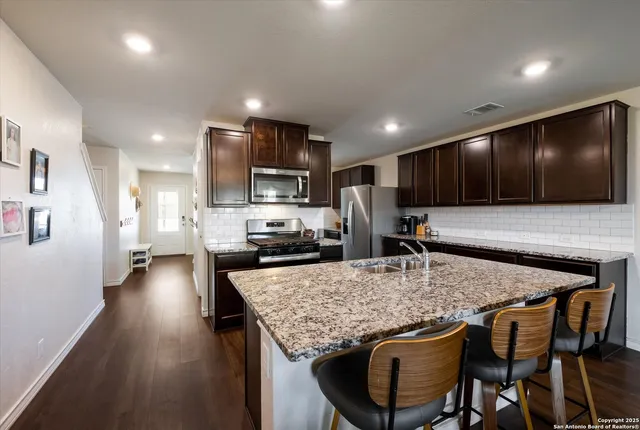 a kitchen with kitchen island granite countertop a stove sink microwave and cabinets