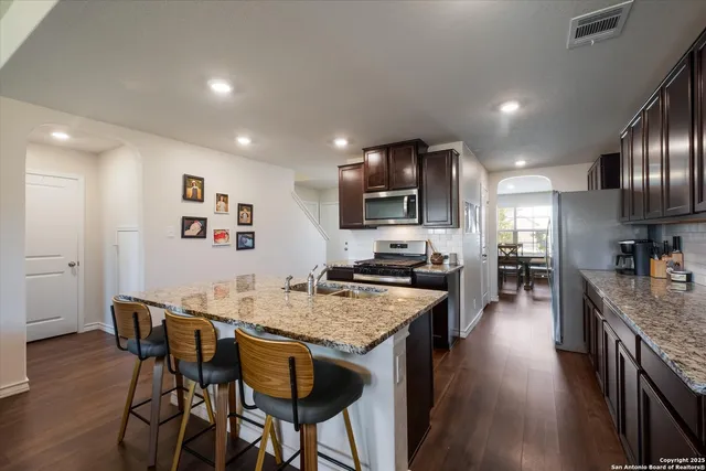 a kitchen with granite countertop kitchen island wooden cabinets and stainless steel appliances