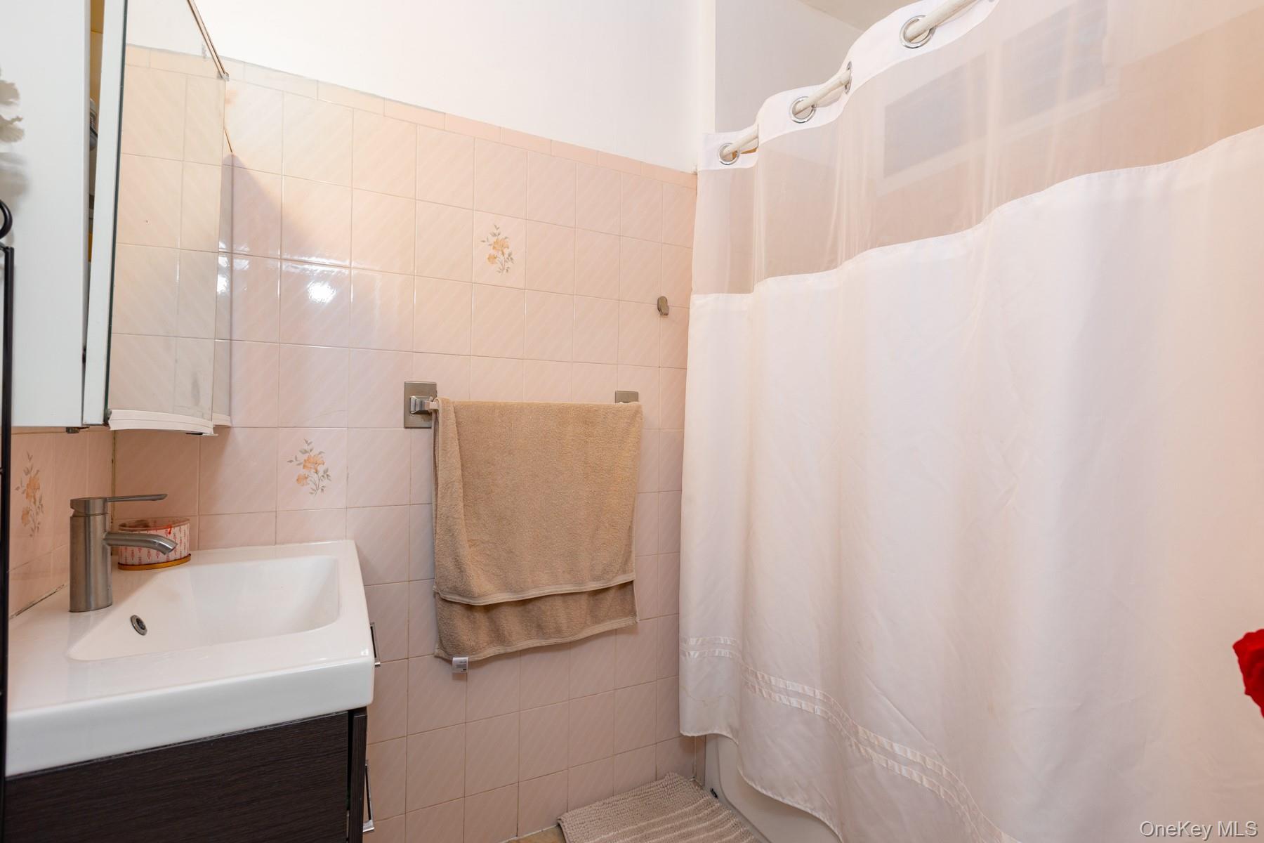 37-33 100th Street Queens, NY 11368 - Photo 11 of 14 Full bath featuring vanity, tile walls, and curtained shower