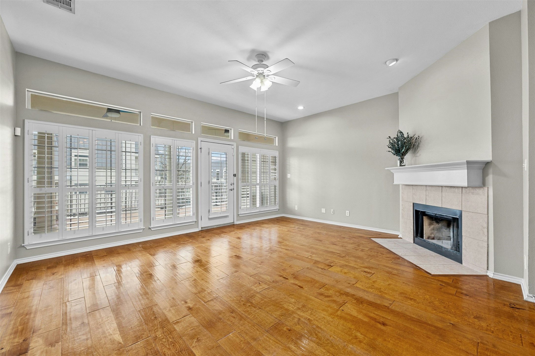2918 Ranch To Market Road 620, Unit W219 Austin, TX 78734 - Photo 14 of 35 Spacious living room featuring a cozy corner fireplace, large windows, and wood flooring throughout.
