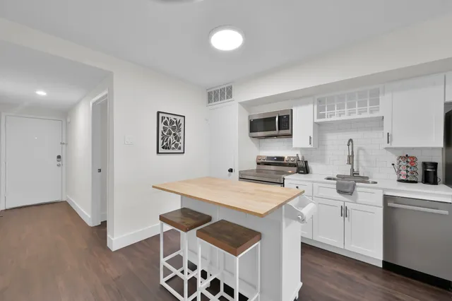 a kitchen that has a sink a stove top oven and white cabinets with wooden floor