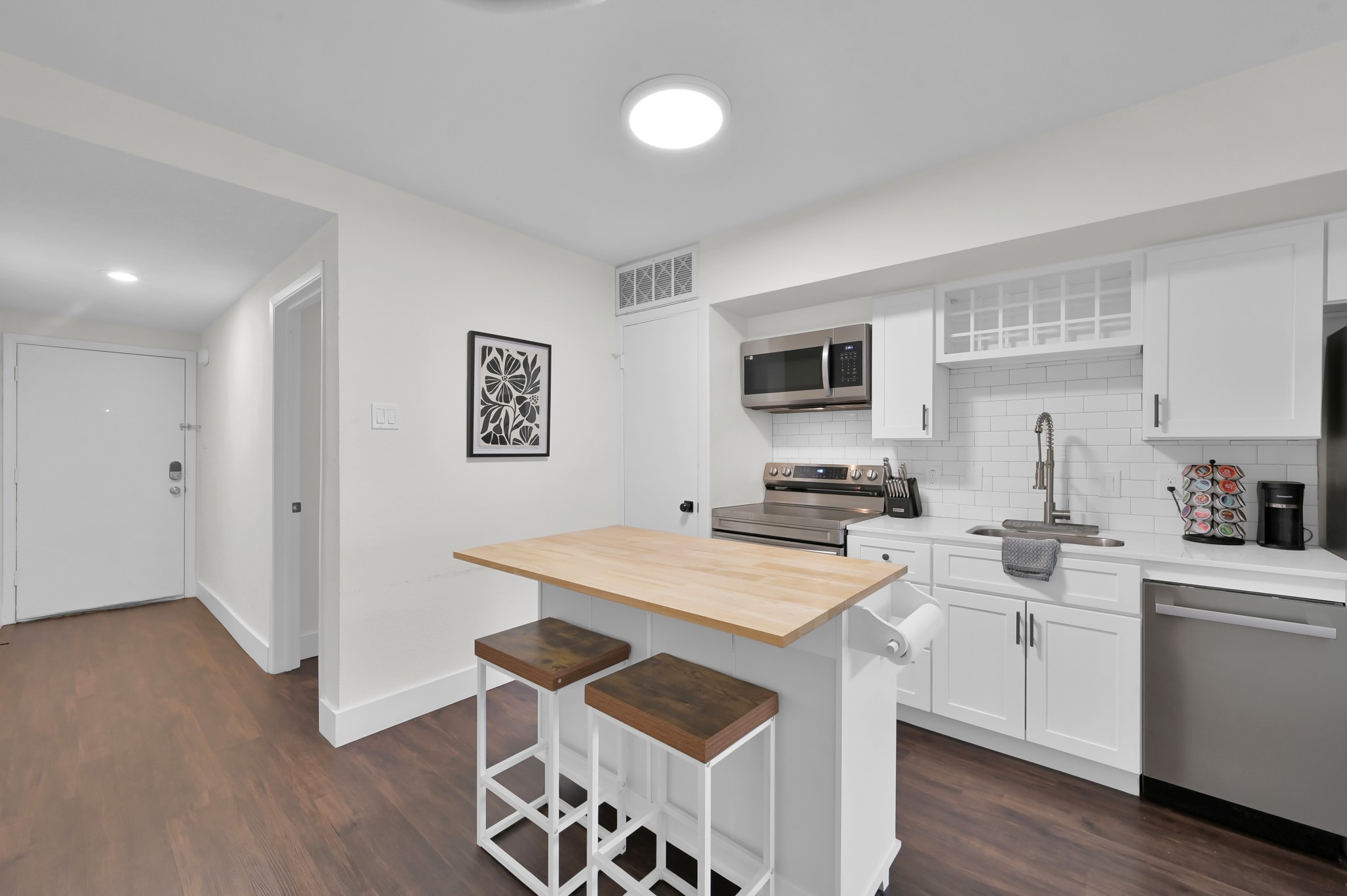 12900 Walden Road, Unit 506E Montgomery, TX 77356 - Photo 3 of 31 a kitchen that has a sink a stove top oven and white cabinets with wooden floor