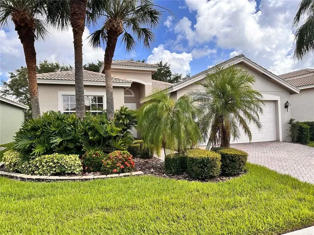 a view of a house with a yard and palm trees