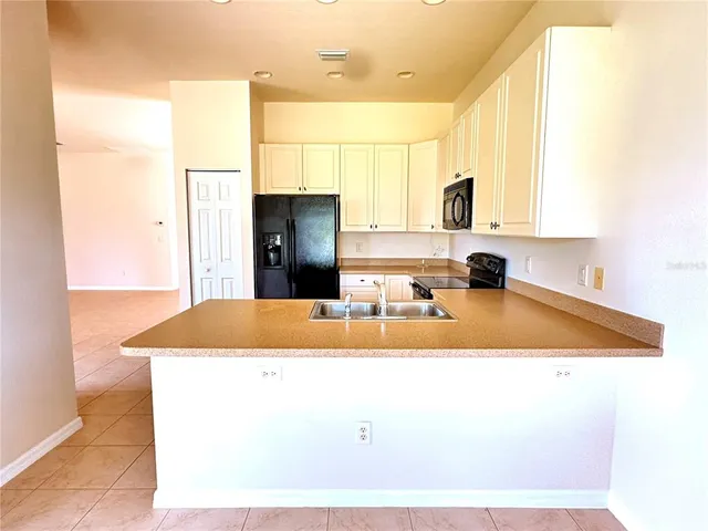 a kitchen with kitchen island granite countertop a sink and a refrigerator