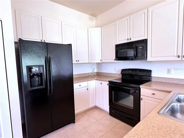 a kitchen with stainless steel appliances granite countertop a refrigerator a sink a stove a microwave and wooden cabinets