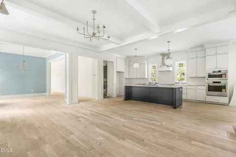 a large white kitchen with kitchen island a sink stainless steel appliances and cabinets
