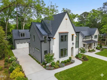 a view of a white house next to a yard with potted plants