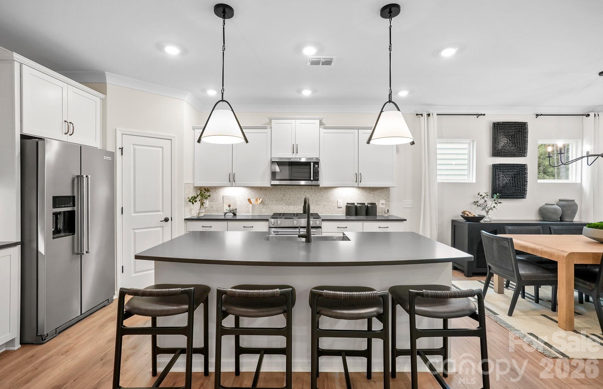 5807 Stewarts Lndg Road, Unit 62 Charlotte, NC 28215 - Photo 2 of 9 a kitchen with granite countertop a table chairs stainless steel appliances and wooden floor