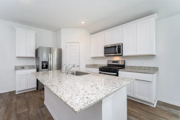 a kitchen with granite countertop stainless steel appliances a sink cabinets and wooden floor