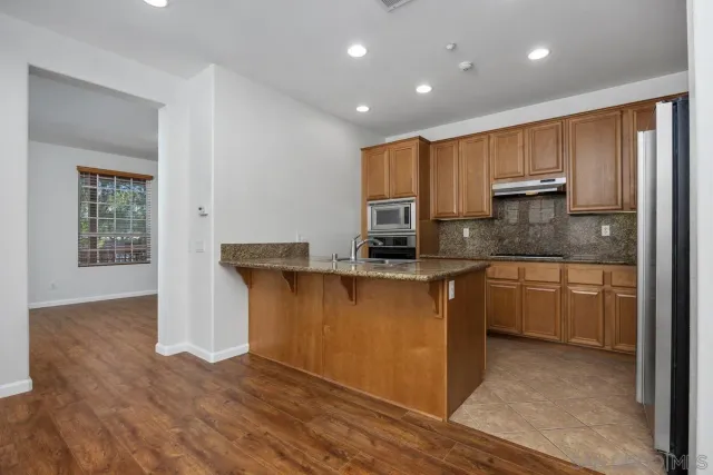 a view of an empty room with wooden floor and closet