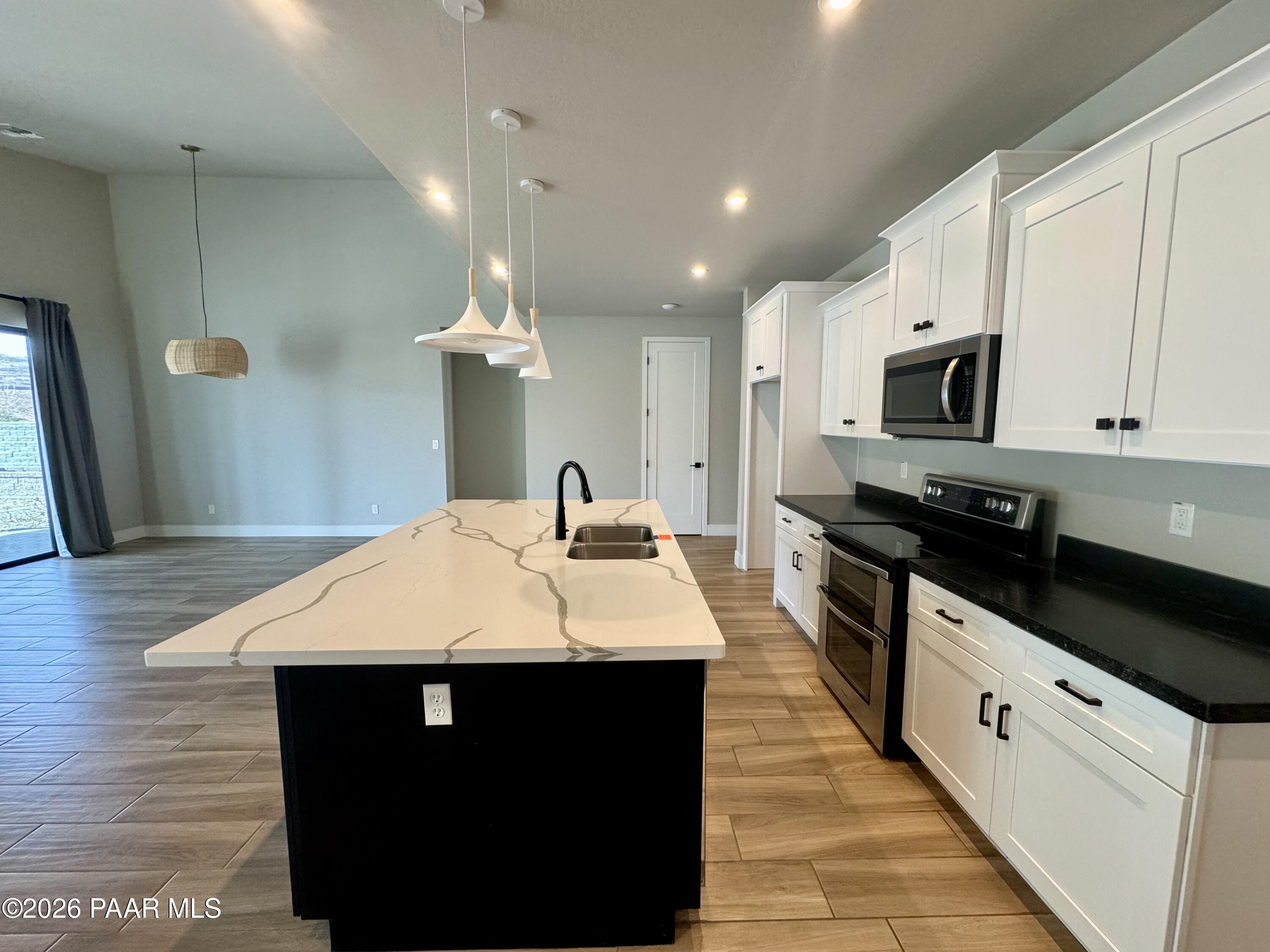 5556 East Killen Loop Prescott Valley, AZ 86314 - Photo 6 of 27 a large kitchen with stainless steel appliances kitchen island granite countertop a stove a sink a refrigerator and a microwave